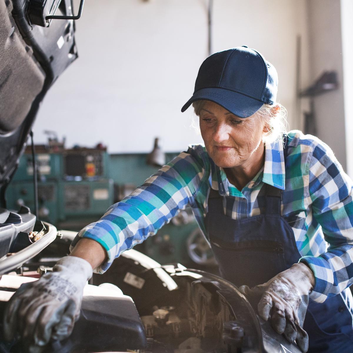 Older Female Mechanic Working on Car in an Auto Repair Shop