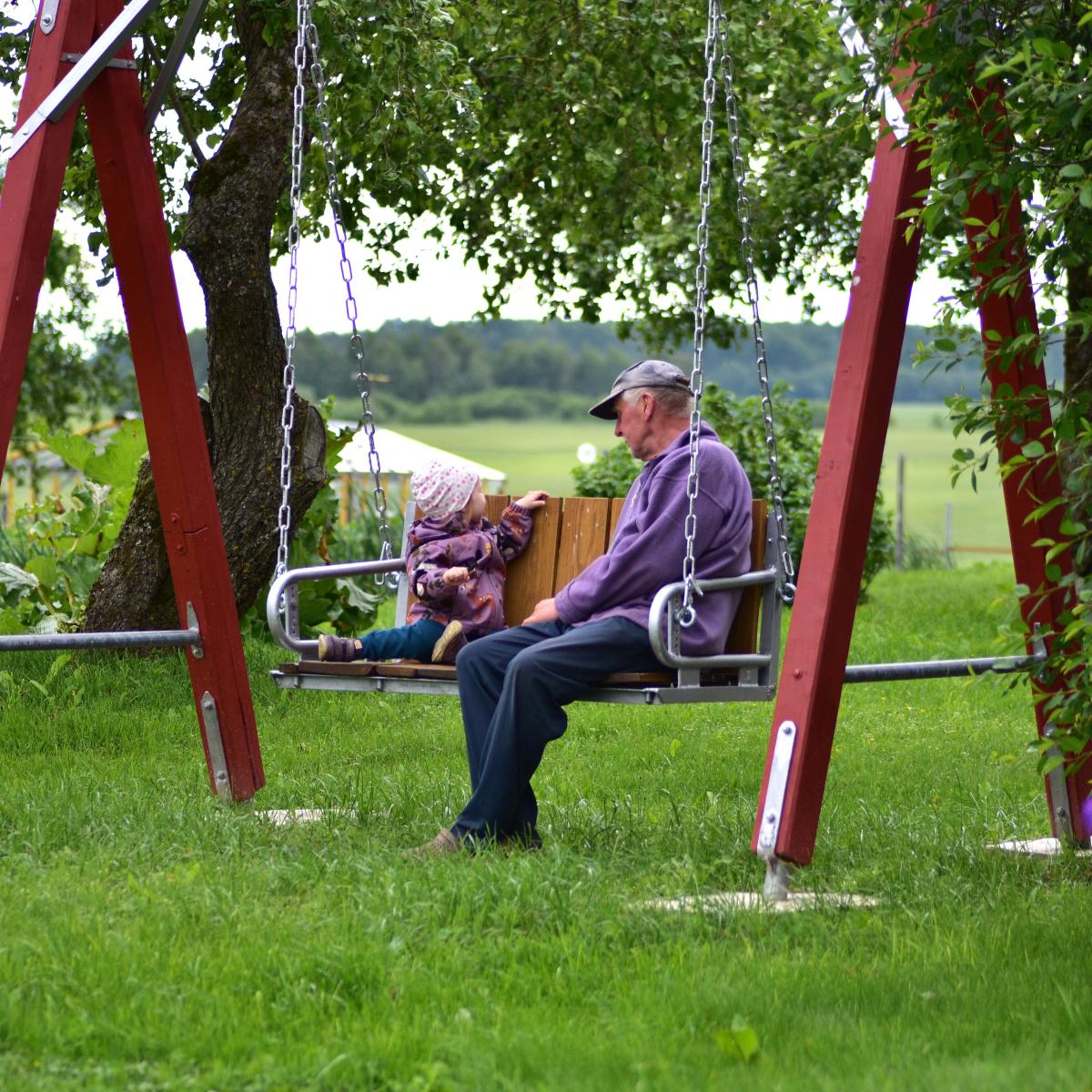 Older Adult Man Sitting in a Swing with a Grandchild