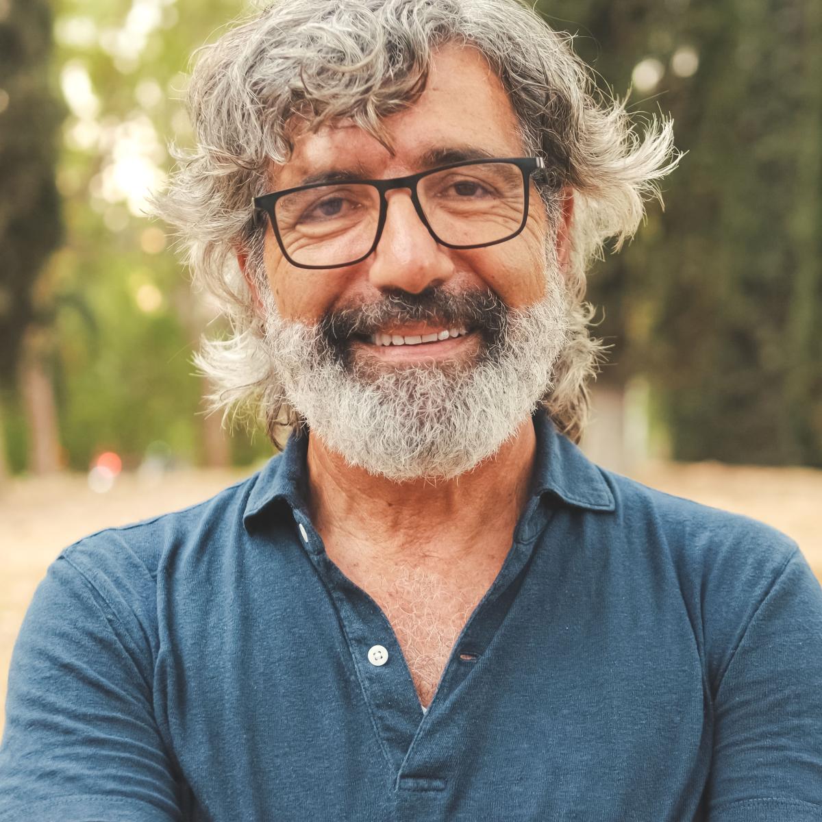Older Adult Man Wearing Glasses in a Blue Button-Down Shirt Smiling at Camera 