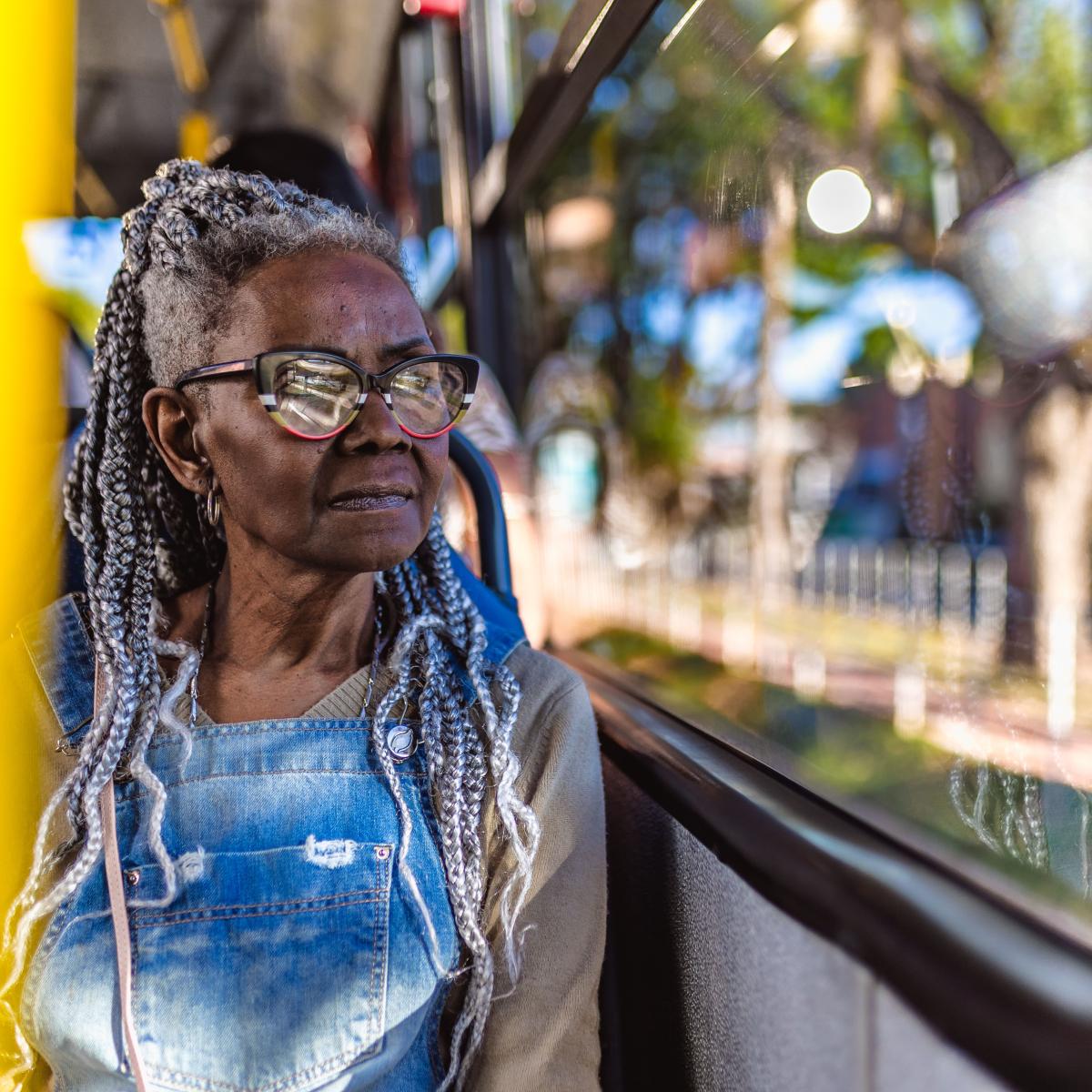 Older adult woman looking out window while riding on bus 