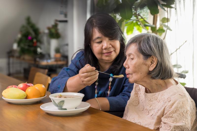 Caregiver assisting older adult with eating.