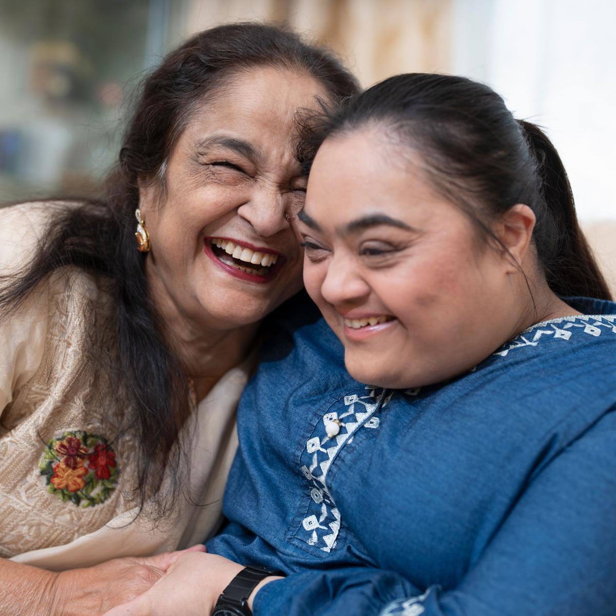 Older adult hugging and laughing with a younger adult