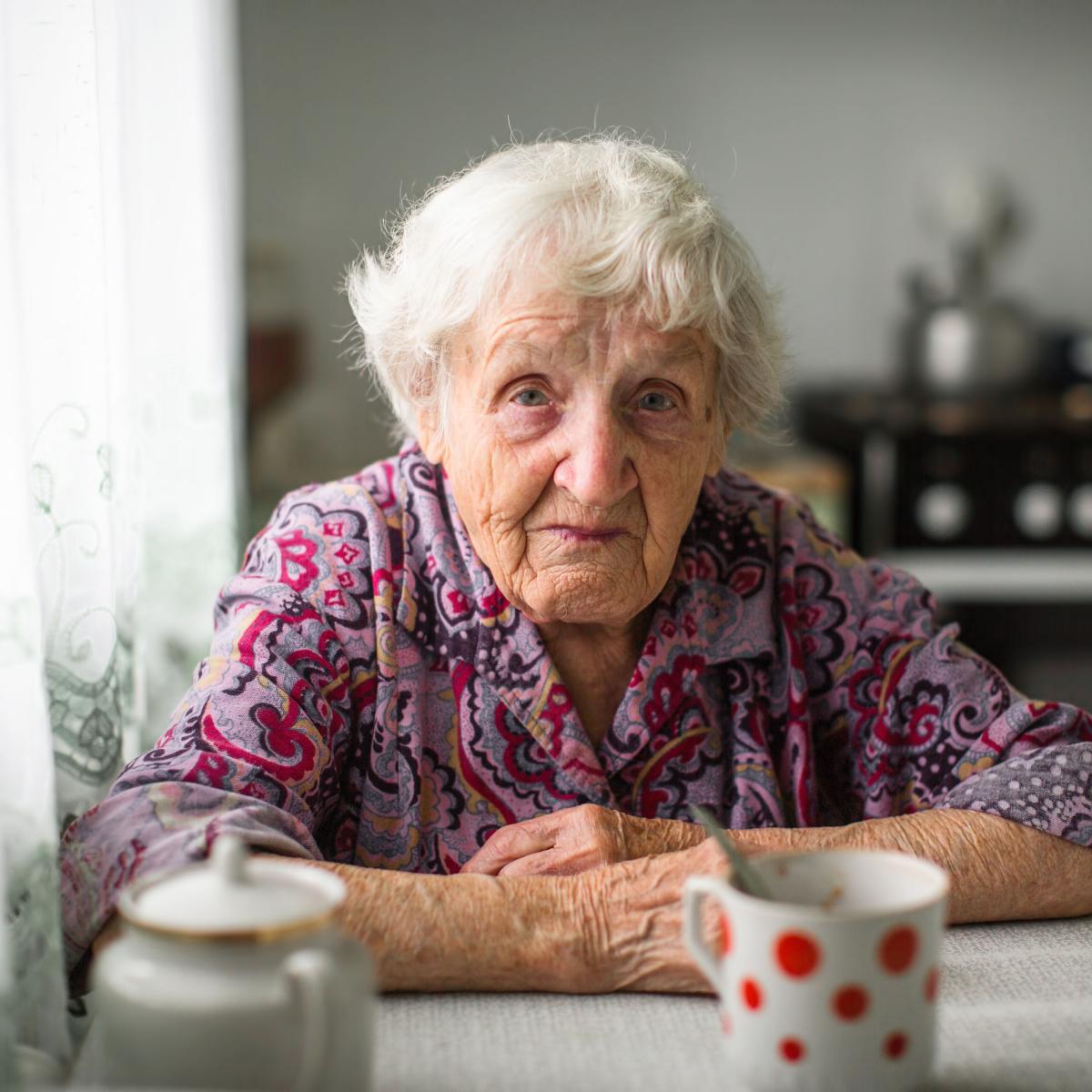Sad older adult sitting at kitchen table