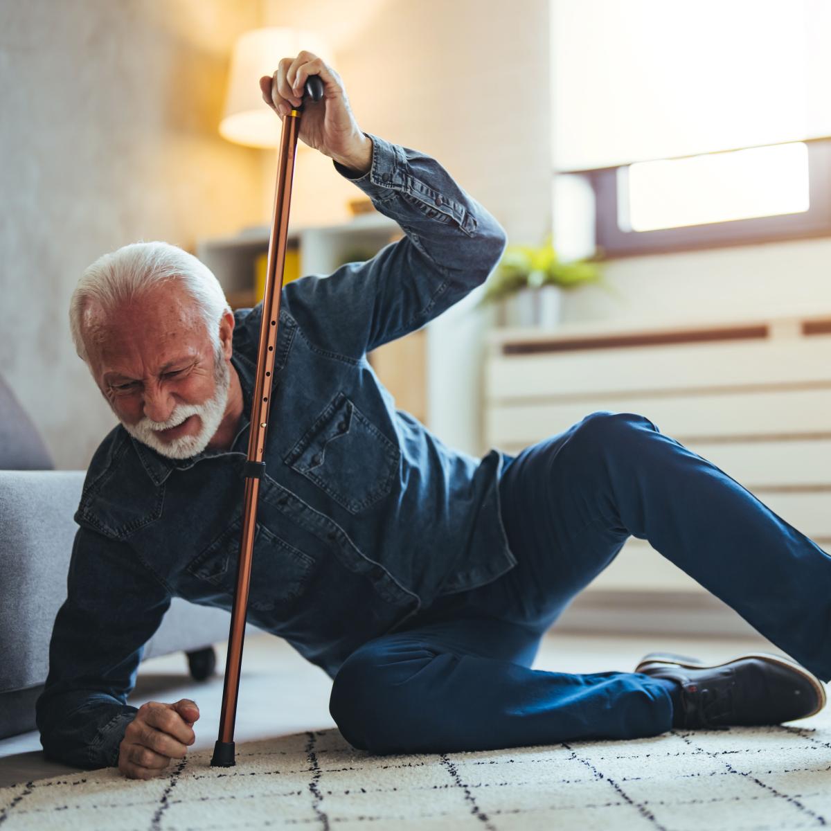 Older adult using cane to rise from a fall to the floor
