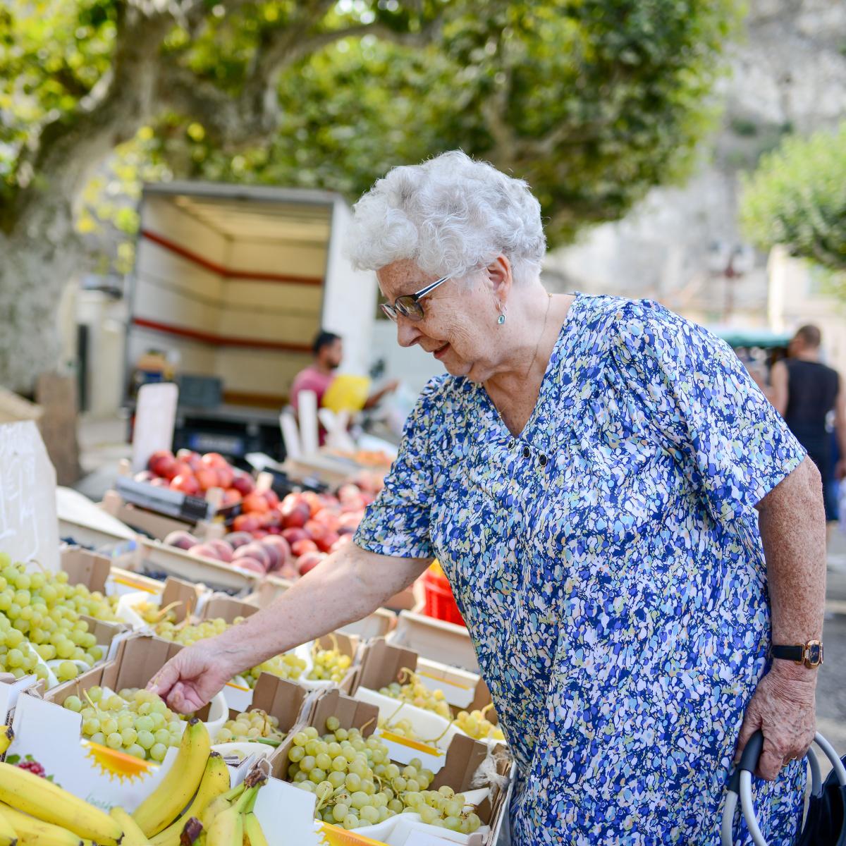 Older adult examining fruit at a farmers market stand